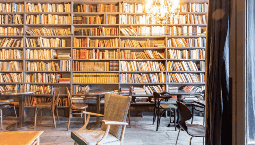 Façade remplie de livre dans le café derrière des tables et des chaises en bois