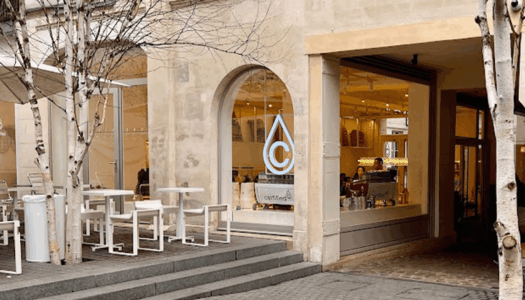 terrasse de cafe a paris avec une grande baie vitrée, des tables et le logo du cafe