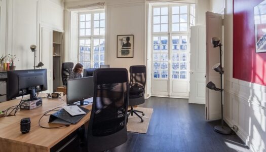 photo d'un open space dans un ancien immeuble avec de grandes fenêtres permettant de faire rentrer la lumière du jour