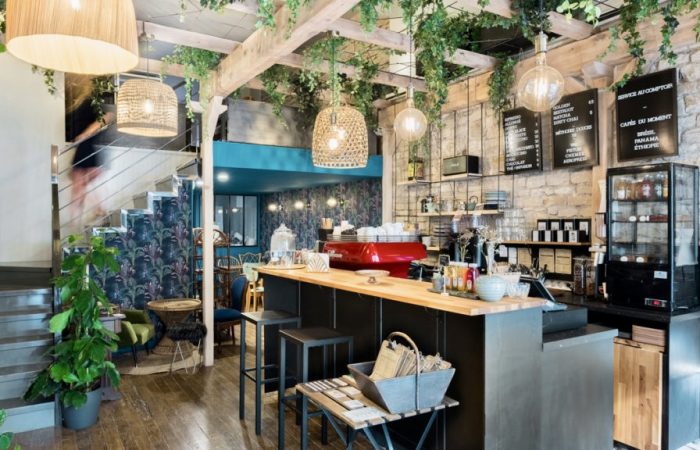 photo intérieur du bar avec vue sur des plantes et le bar ainsi que l'escalier pour accéder aux tables à l'étage