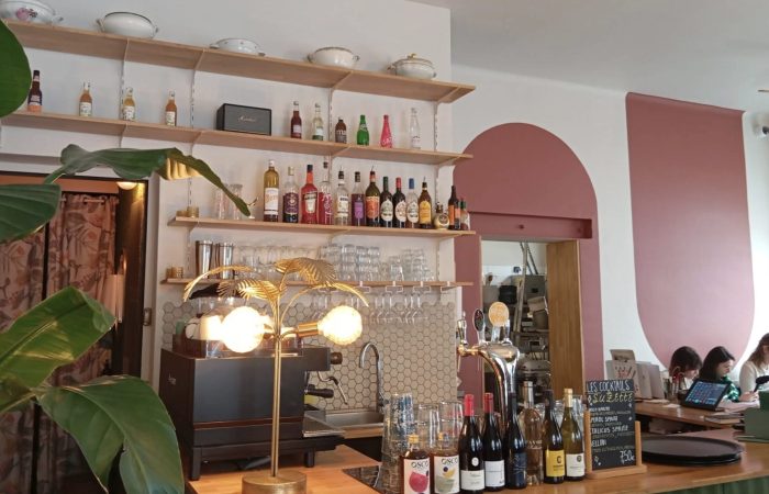 photo de l'intérieur du café, vue sur le bar coloré avec différentes bouteilles et des tables sur le côté