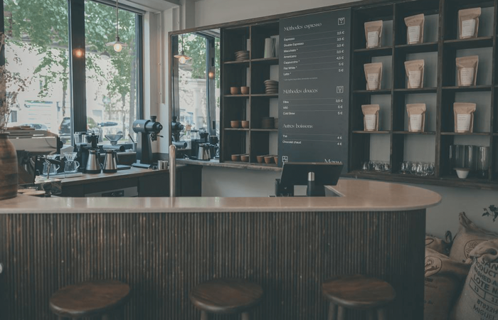 Bar d'un café avec tabourets et le menu sur le mur. La décoration est sombre et a beaucoup de bois