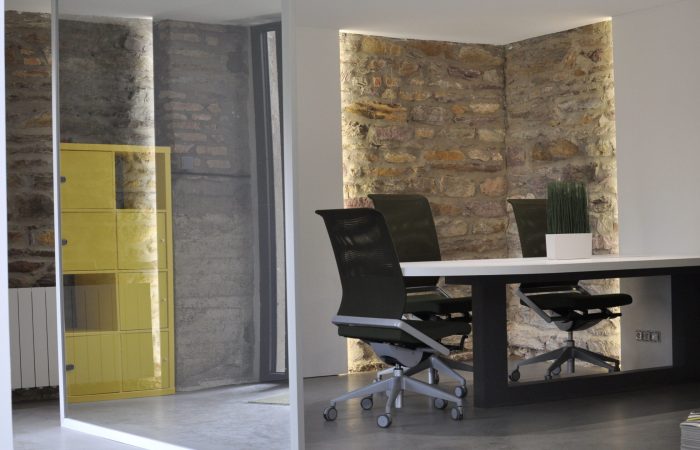 photo de l'intérieur de l'espace de coworking avec bureaux et chaises avec des murs en pierre