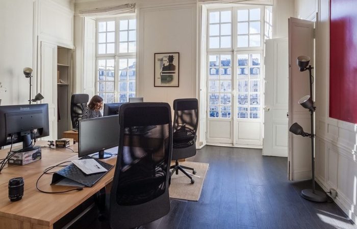 photo d'un open space dans un ancien immeuble avec de grandes fenêtres permettant de faire rentrer la lumière du jour